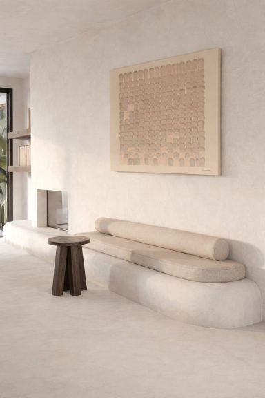 Sala minimalista con un sofá curvo, una mesa de café y una obra de arte en la pared.